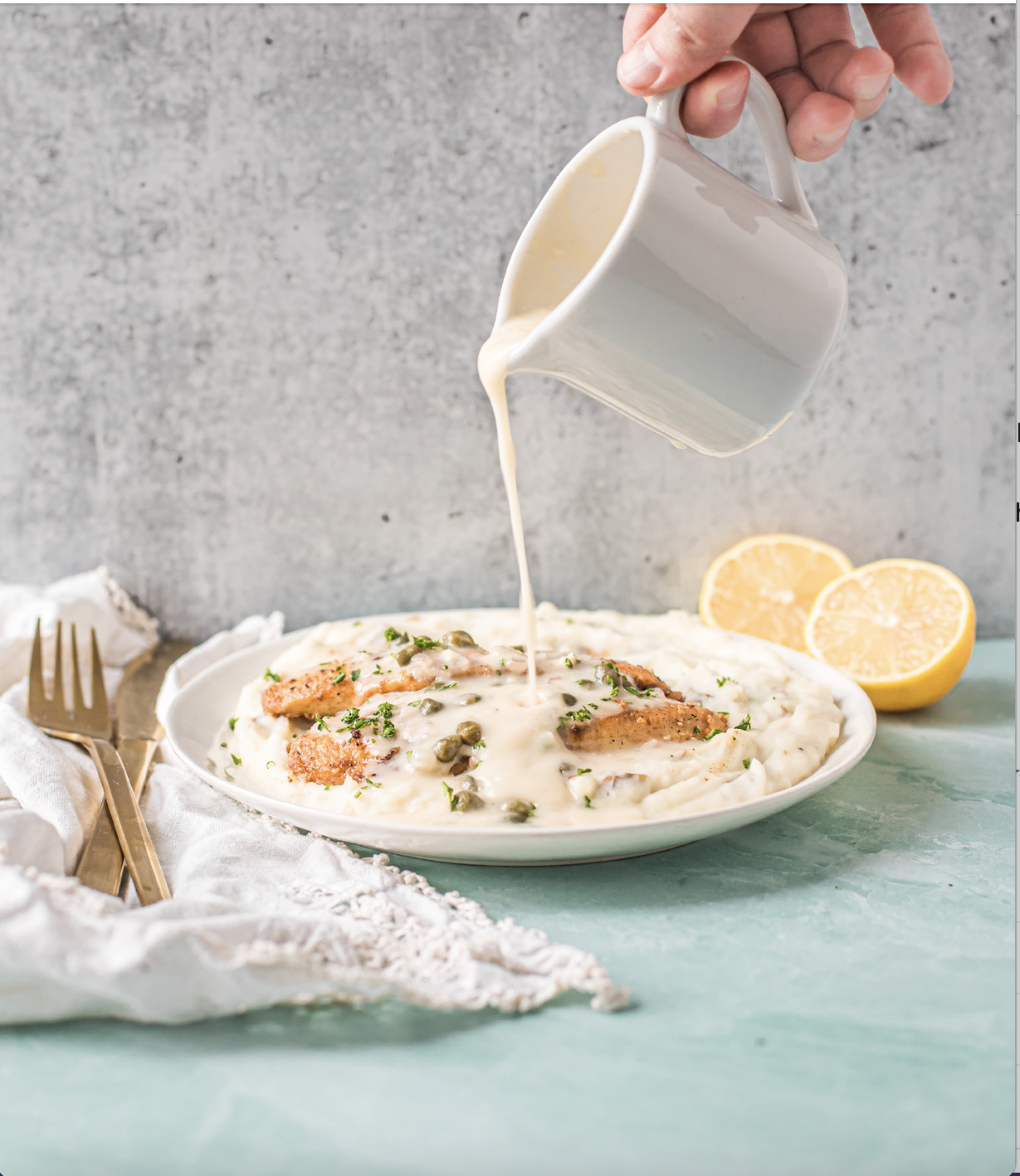 Creamy lemon caper sauce being poured over chicken and mashed potatoes, garnished with parsley
