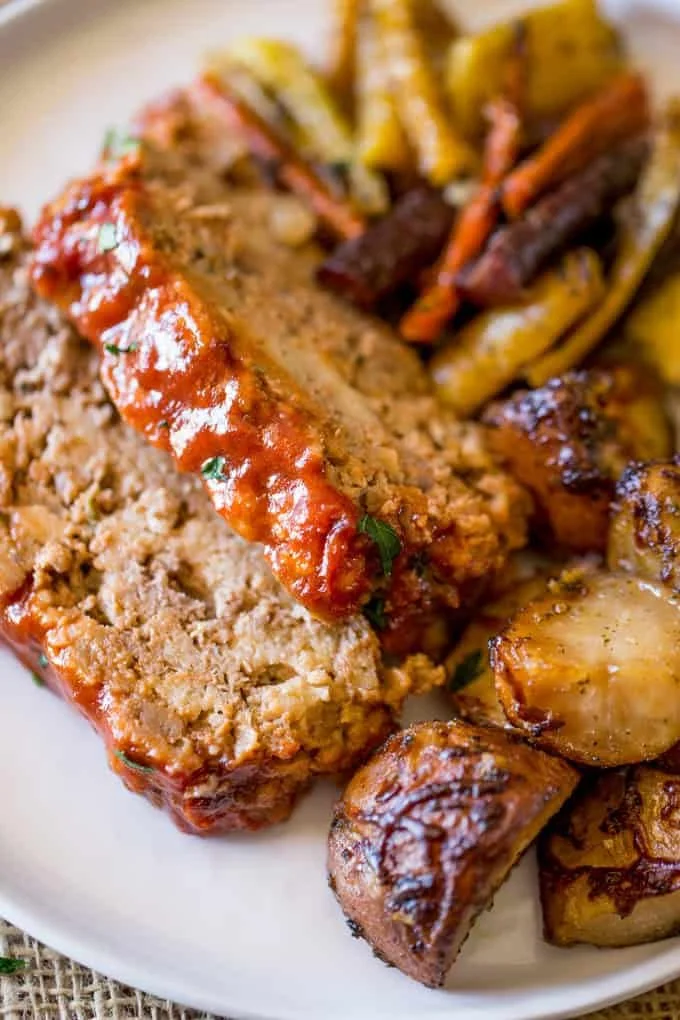 Sliced meatloaf topped with tomato glaze, served with roasted potatoes and carrots
