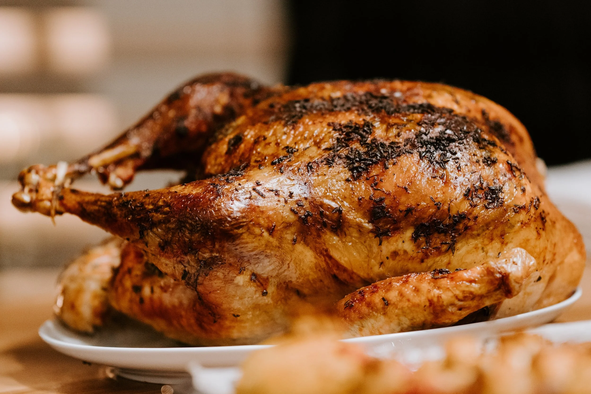 Whole roasted turkey with crispy, herb-seasoned golden-brown skin, served on a white platter