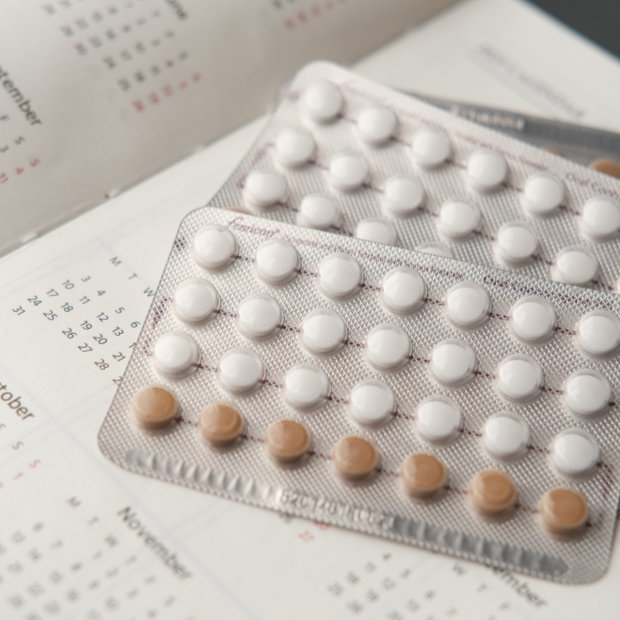 Birth control pill blister packs resting on a calendar page